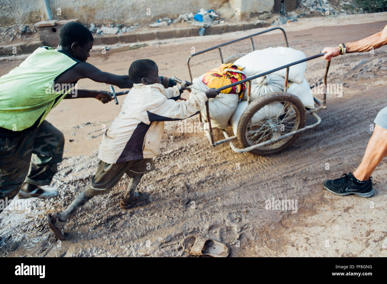 Mali, Afrika - kaukasischen reifer Mann schwarzen afrikanischen Kindern zu helfen, mit einem Essen in der Nähe von Bamako Stockfoto