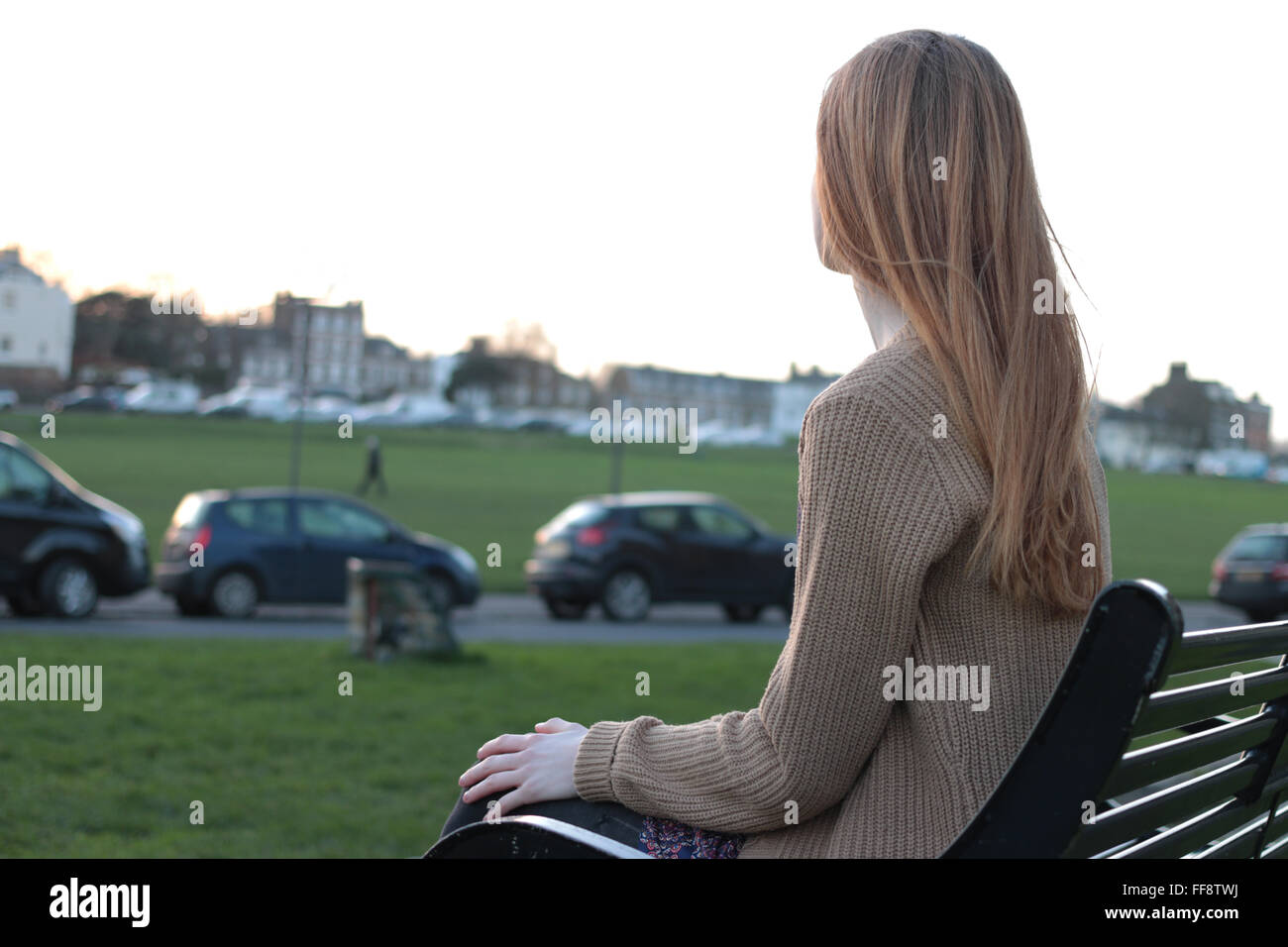 Junge nachdenkliche Frau sitzen auf einer Bank, Blick in die Ferne. Stockfoto
