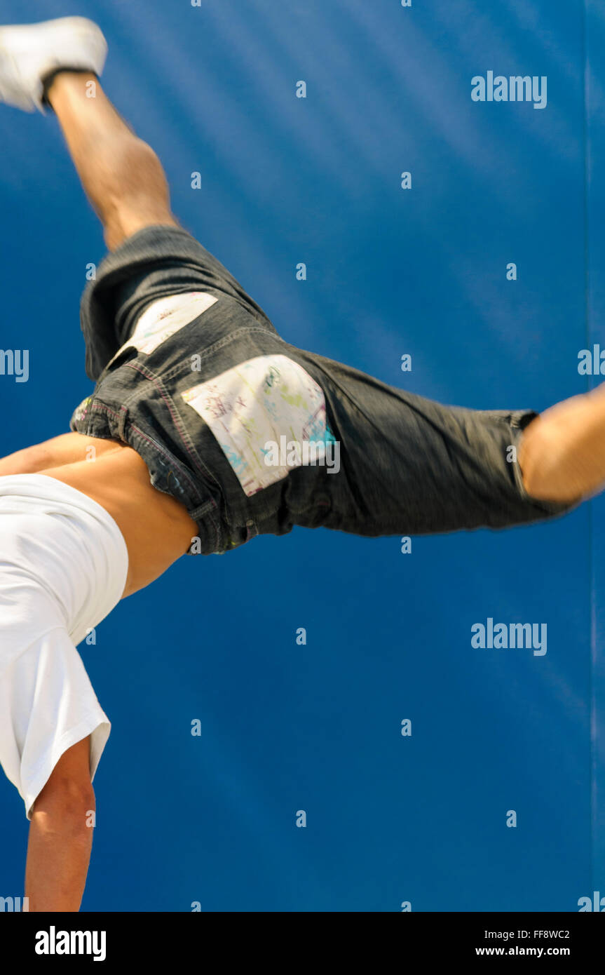 Rückansicht der ein junger Mann-Breakdance mit beiden Beinen in der Luft. Stockfoto