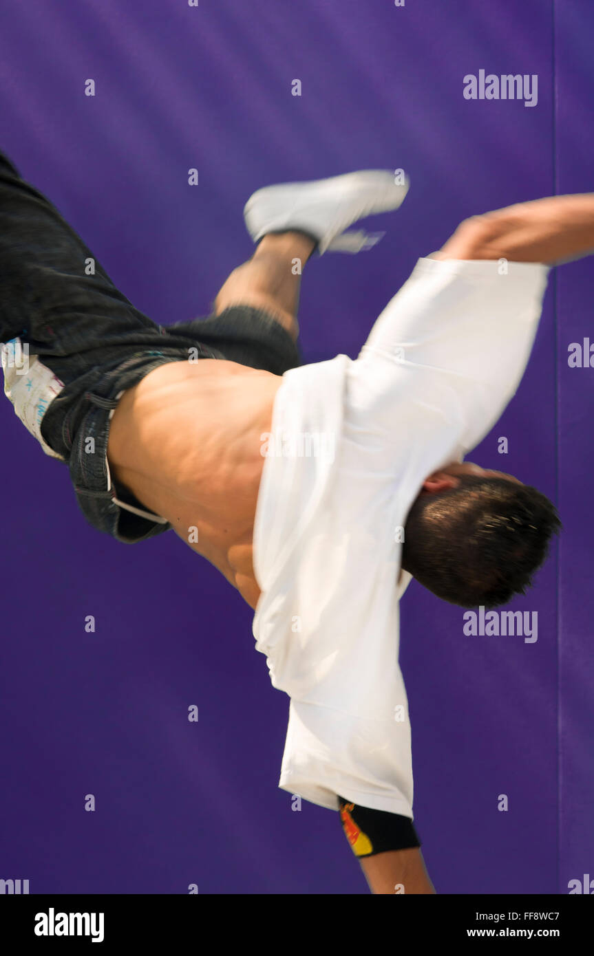 Rückansicht der ein junger Mann-Breakdance mit beiden Beinen in der Luft. Stockfoto