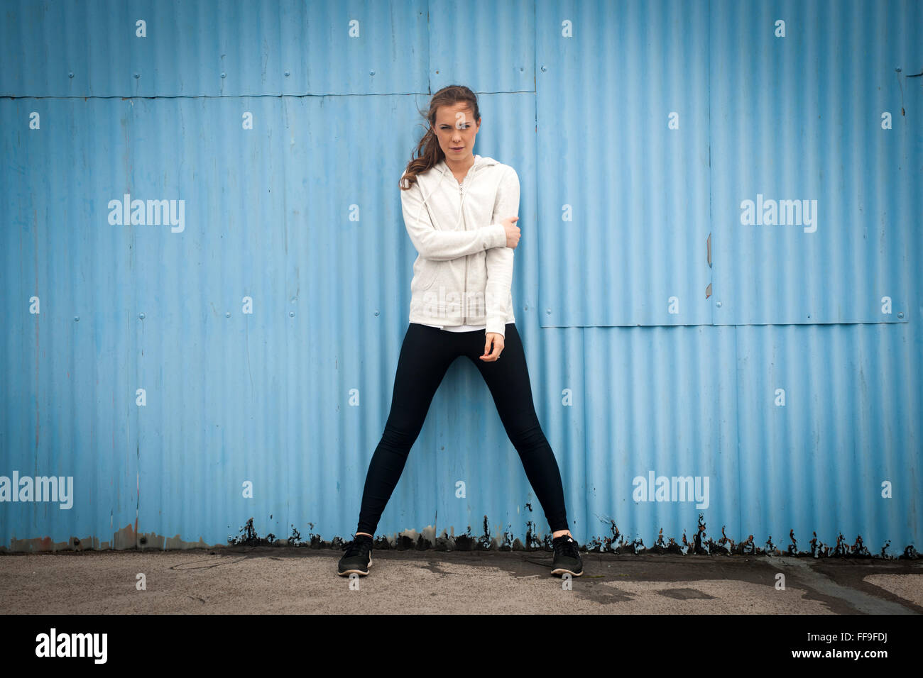 Frau stehend durch eine blaue Wellblech Wand tragen sportswear Stockfoto