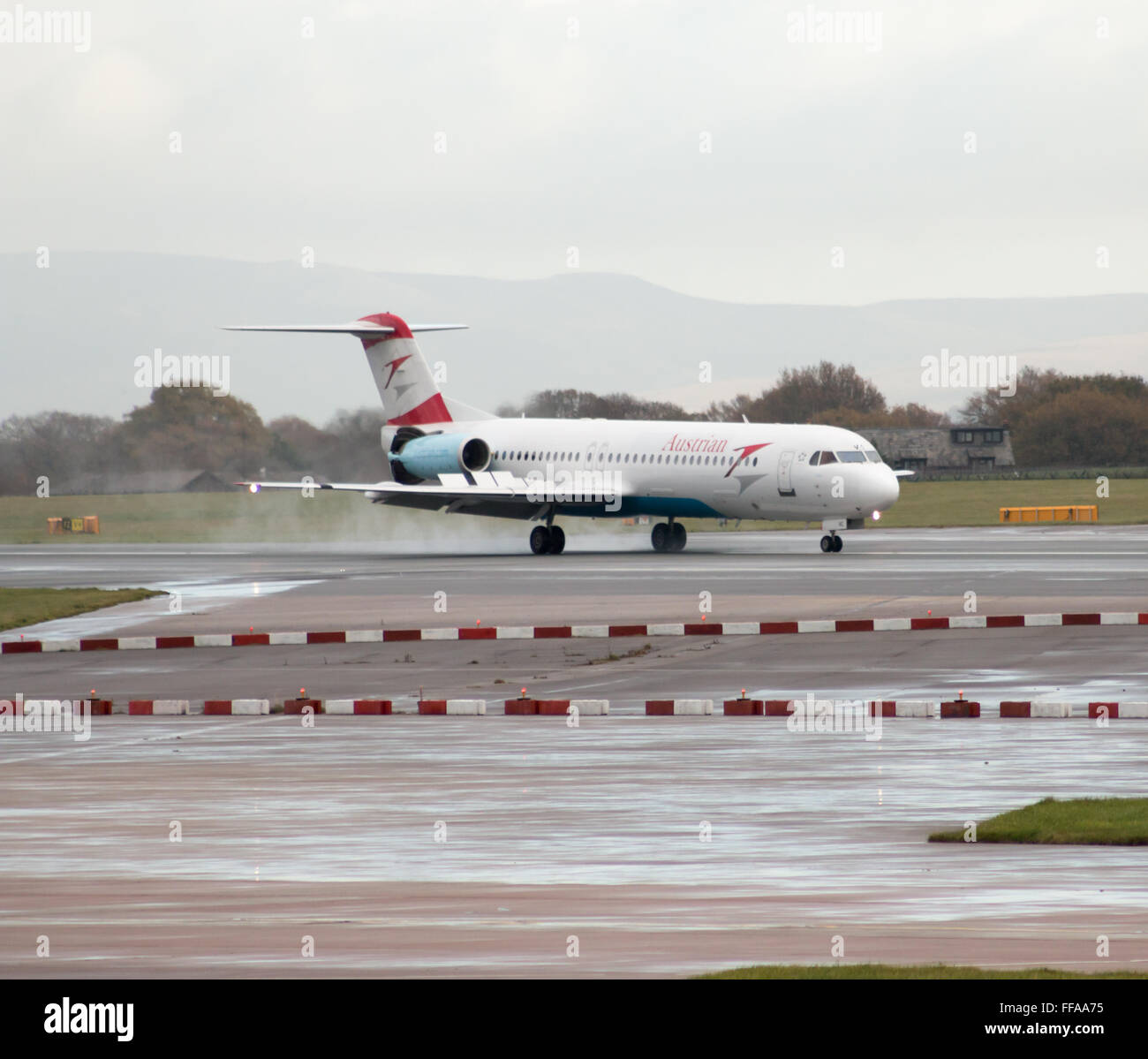 Austrian Airlines Fokker 100 mittelständische Twin-Turbinen-Kreiselbegläse Passagierflugzeug auf Manchester International Airport Asphalt Rollen. Stockfoto