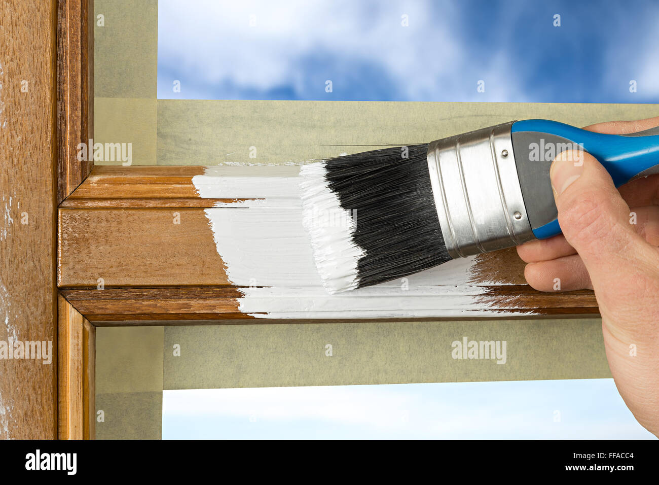 Pinting eines Fensterrahmens mit weißer Farbe Stockfoto