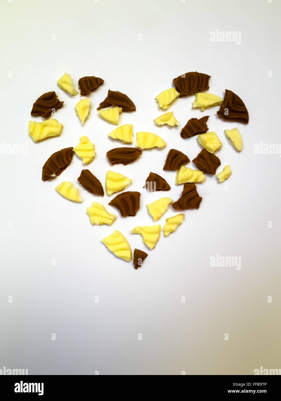 Herzform gemacht von weißer und dunkler Schokolade Fragmente auf weißem Hintergrund Stockfoto