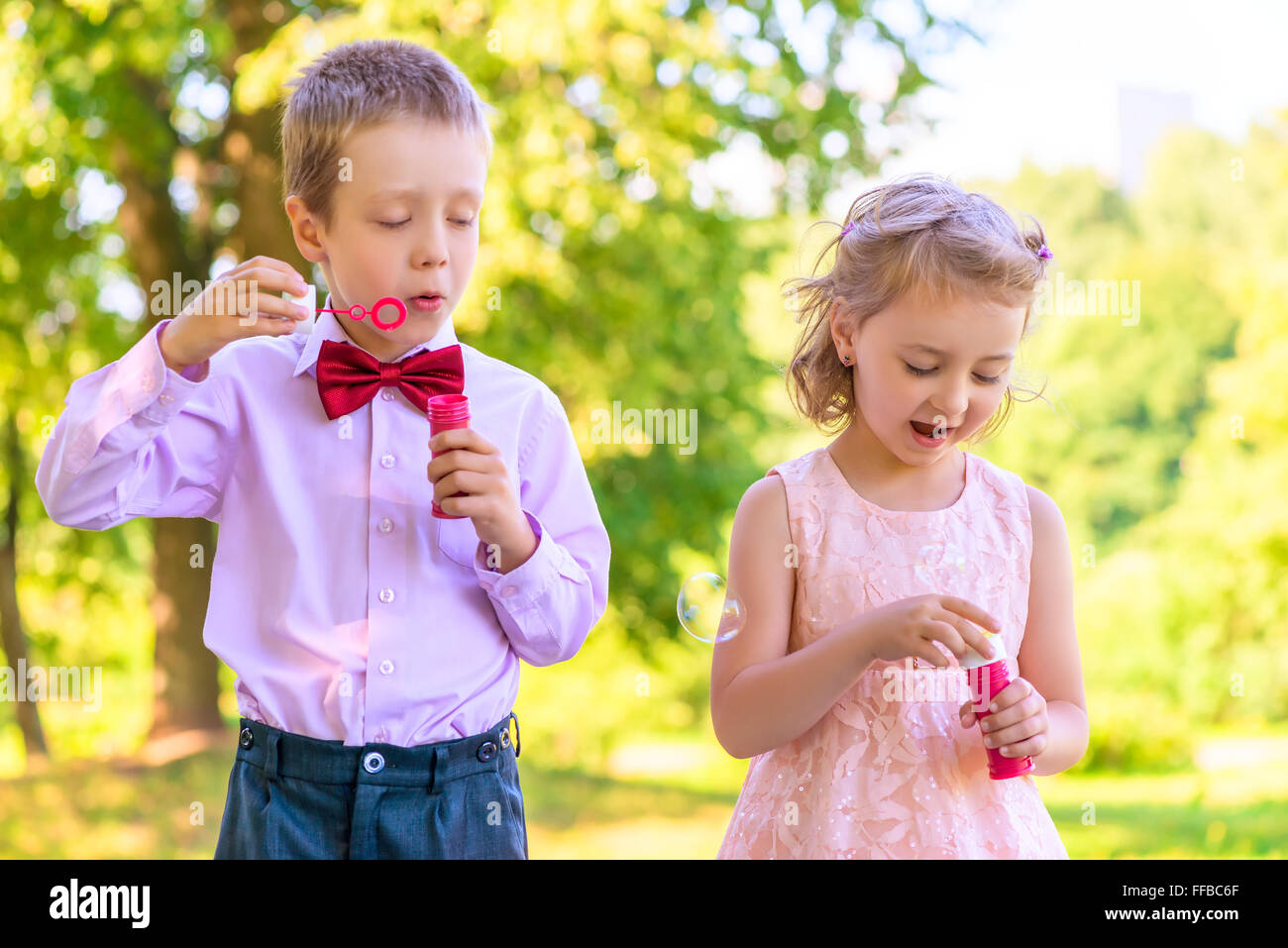 junge und ein Mädchen von 6 Jahren auf der Wiese mit bubbles Stockfoto