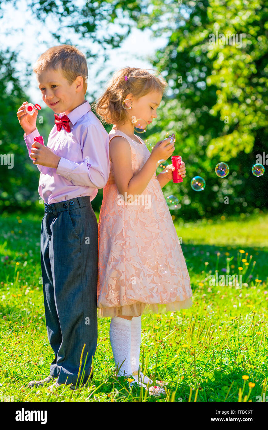 Vertikale Aufnahme der Kinder von 6 Jahren mit Seifenblasen auf Natur Stockfoto