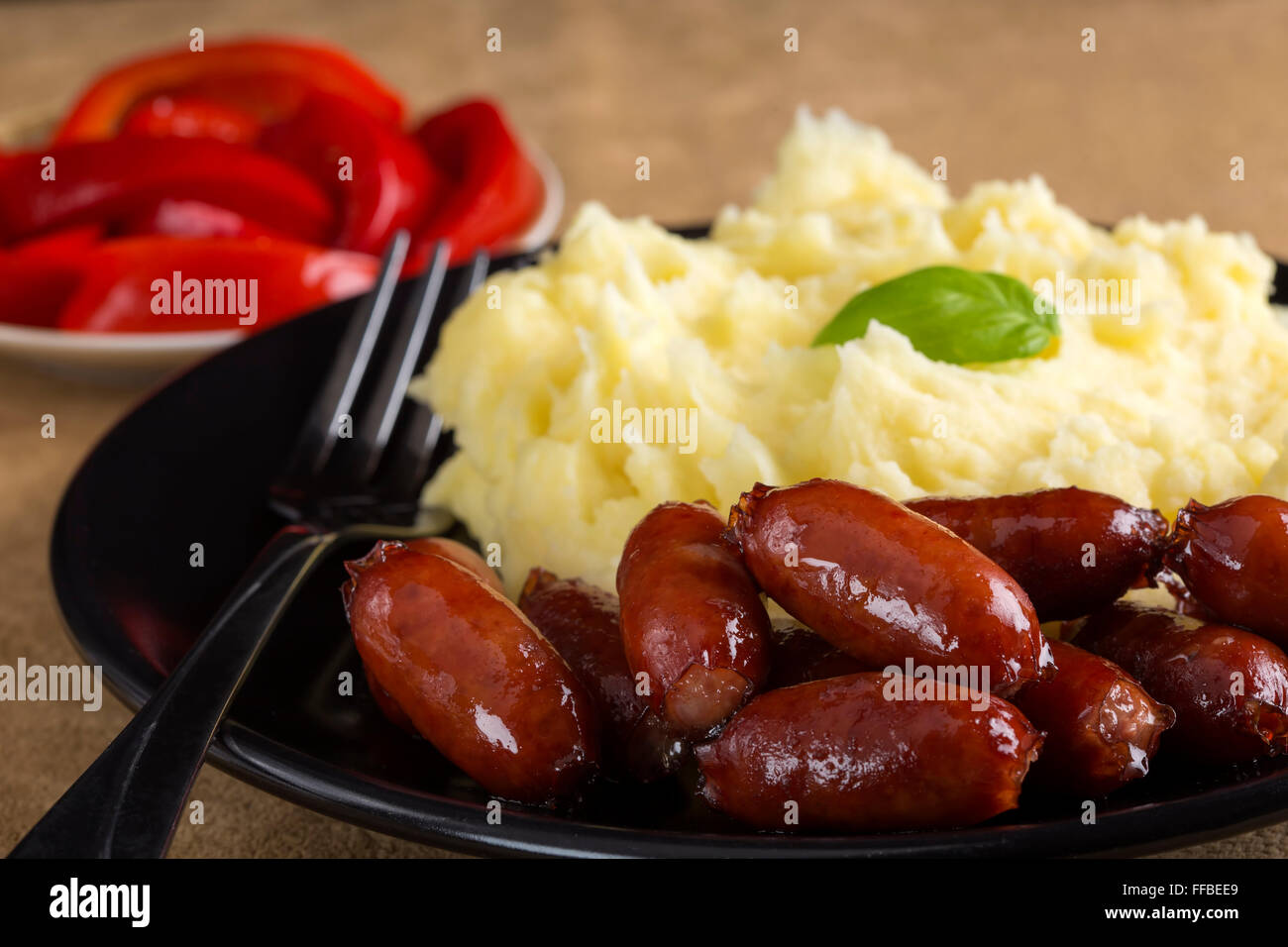 Würstchen und Kartoffelbrei mit Gurken im Hintergrund Stockfoto