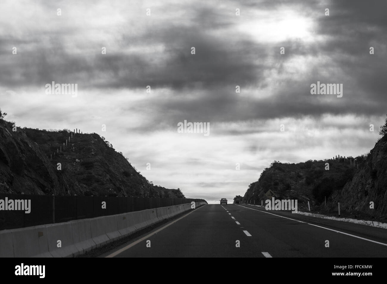 Ein Auto läuft auf der Straße in der Wüste unter dem grauen Himmel. Es ist so allein. Wo ist die Zukunft? Stockfoto