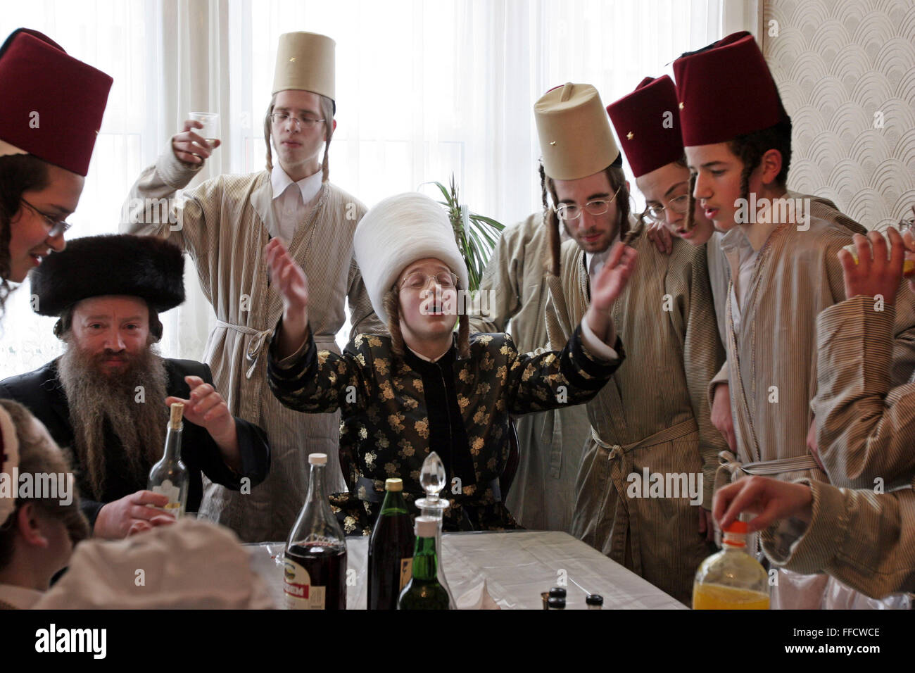 Während des jüdischen Festivals von Purim besucht eine Gruppe von orthodoxen jüdischen Jungen aus der Viznitz-Jeschiwa (Schule) verkleidet lokale Geschäftsleute, Geld für ihre Schule zu sammeln. Die Purim Rabbiner (Mitte) führt die Gruppe mit einem Lied, sie trinken Alkohol in jedem Haus, die sie im Laufe des Tages zu besuchen. Stockfoto