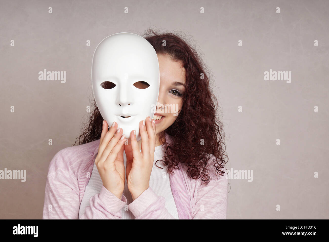 glückliches Mädchen spähen hinter Maske Stockfoto