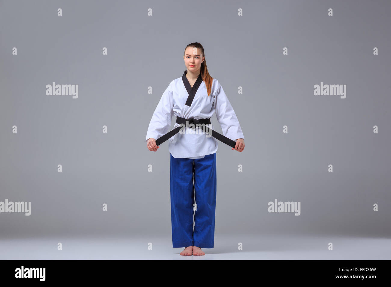 Das Karate Mädchen in weißen Kimono und Black Belt grauen Hintergrund überragt. Stockfoto