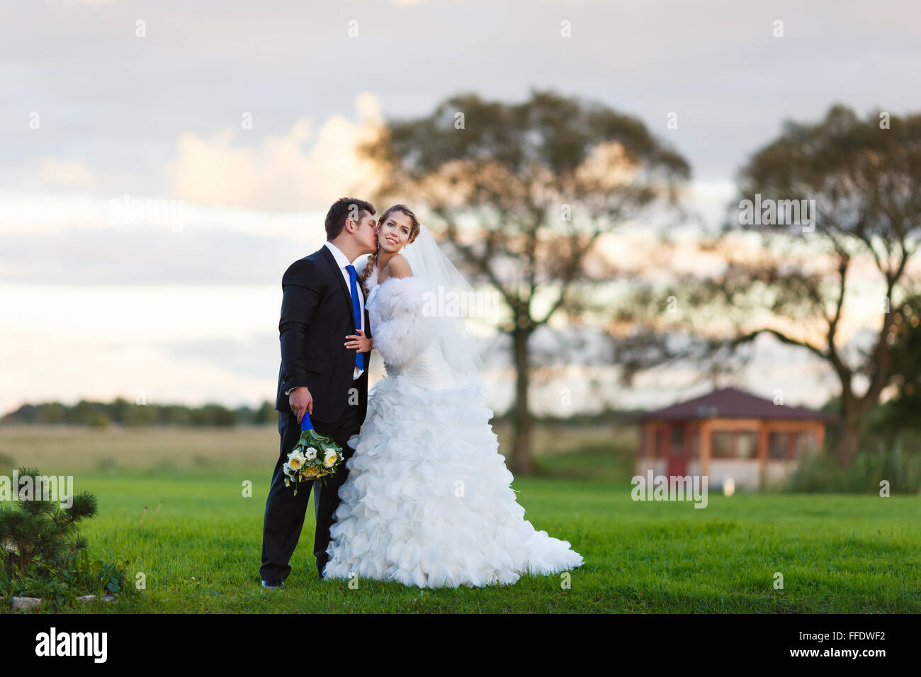 Glückliches Hochzeitspaar zu Fuß entlang der Bereich umarmen und küssen am Abend Stockfoto