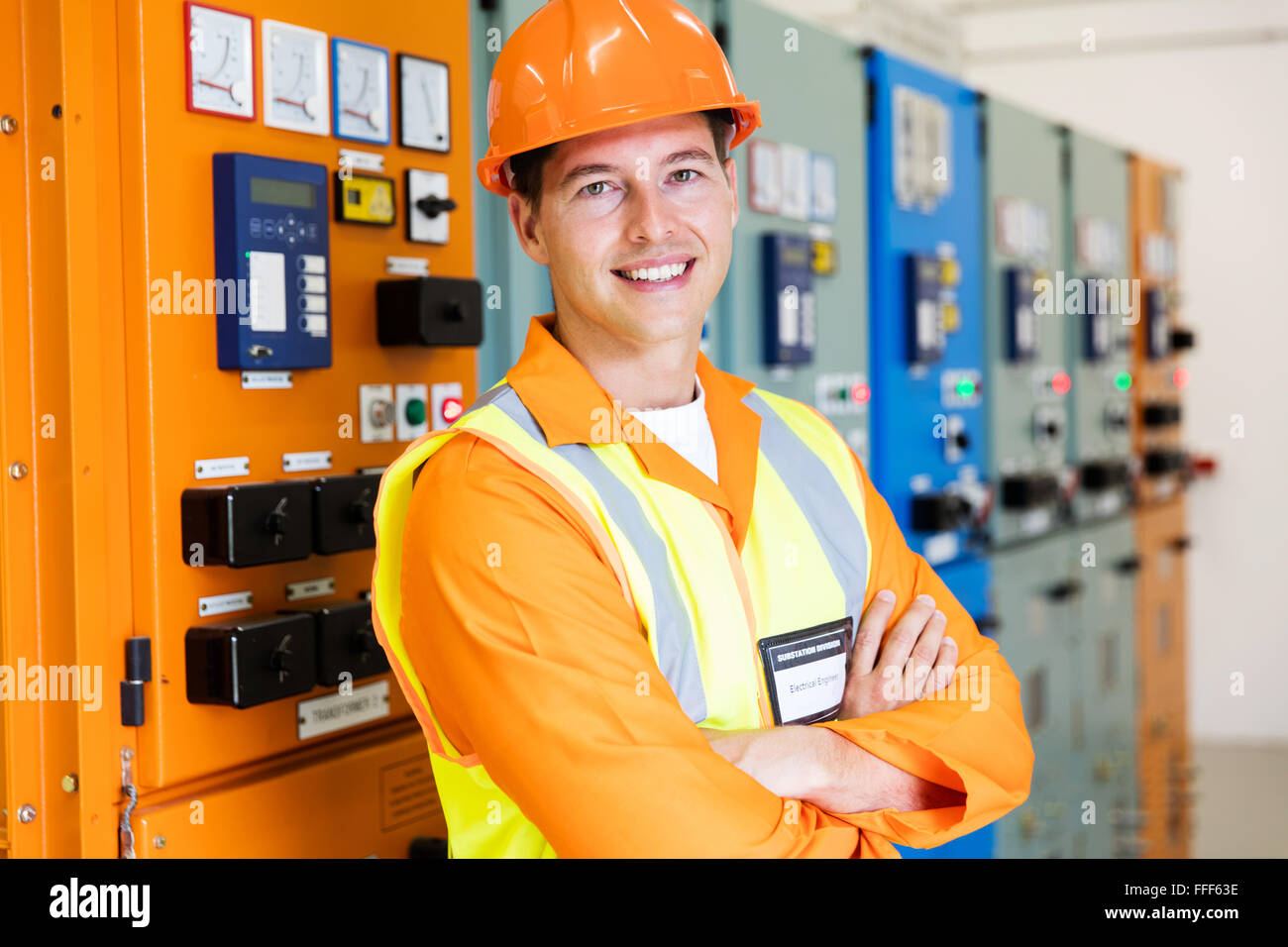 hübscher Junge Elektrotechniker mit Armen kreuzten sich im Kontrollraum Stockfoto