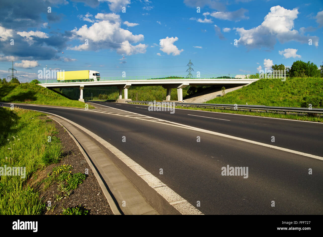 Brücke über eine leere Autobahn in der Landschaft, LKW, gehen über die Brücke, blauer Himmel mit weißen Wolken Stockfoto