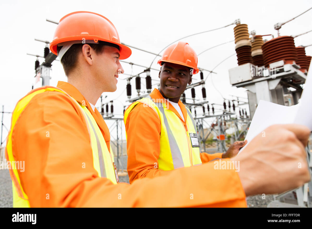 macht Unternehmen Elektriker diskutieren Blaupause im Umspannwerk Stockfoto