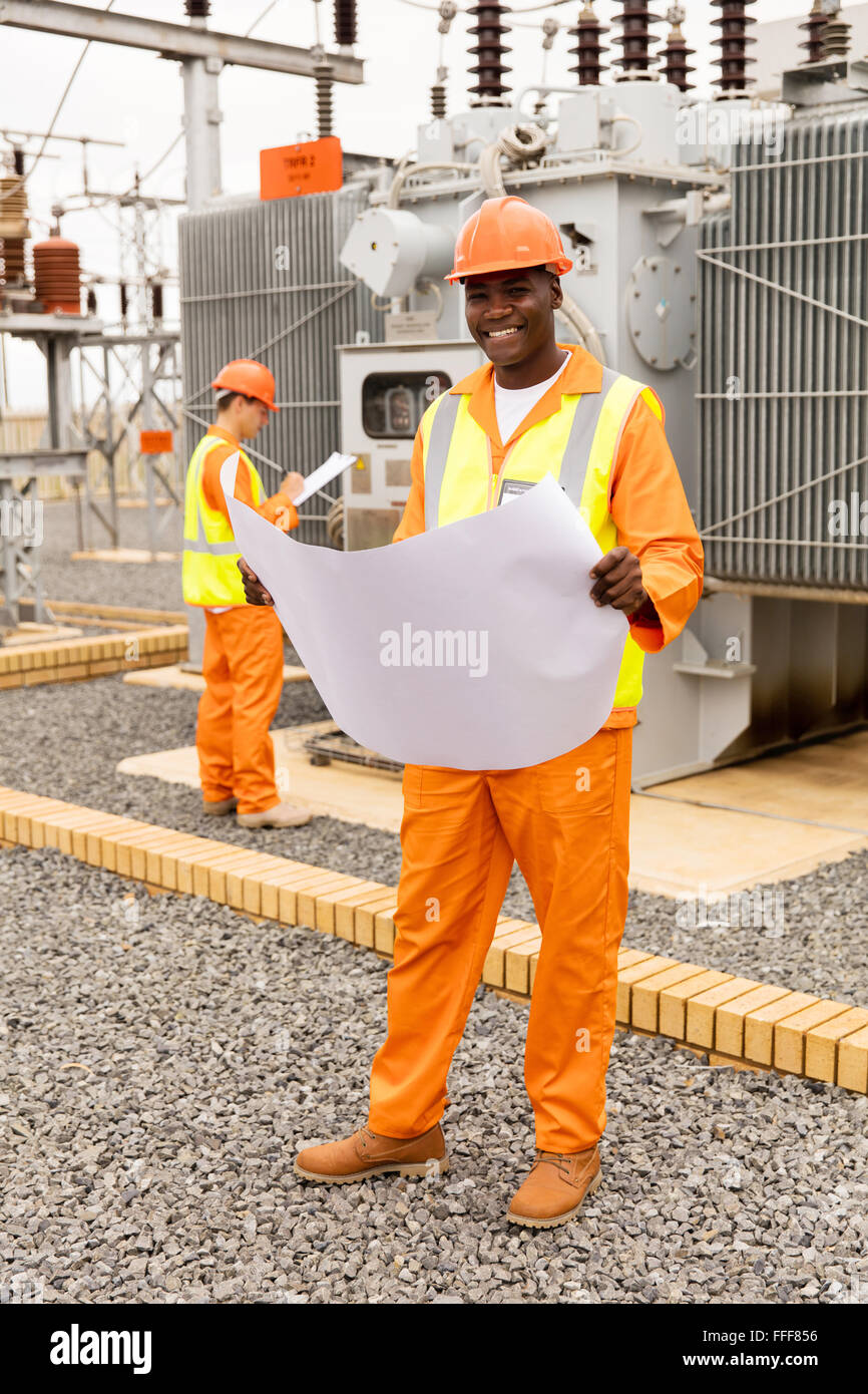 Porträt der schönen afrikanischen Elektro Ingenieur mit Blaupause im Umspannwerk Stockfoto