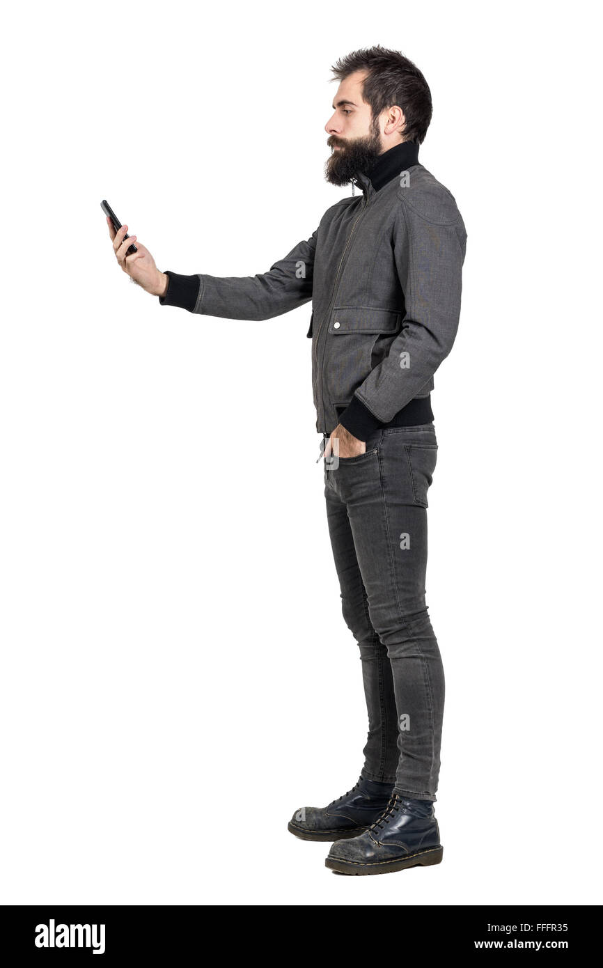 Seriöse stilvolle punker in graue Jacke Selfie Foto. Seitenansicht. Ganzkörper-Länge-Porträt isoliert auf weißem Hintergrund Stockfoto