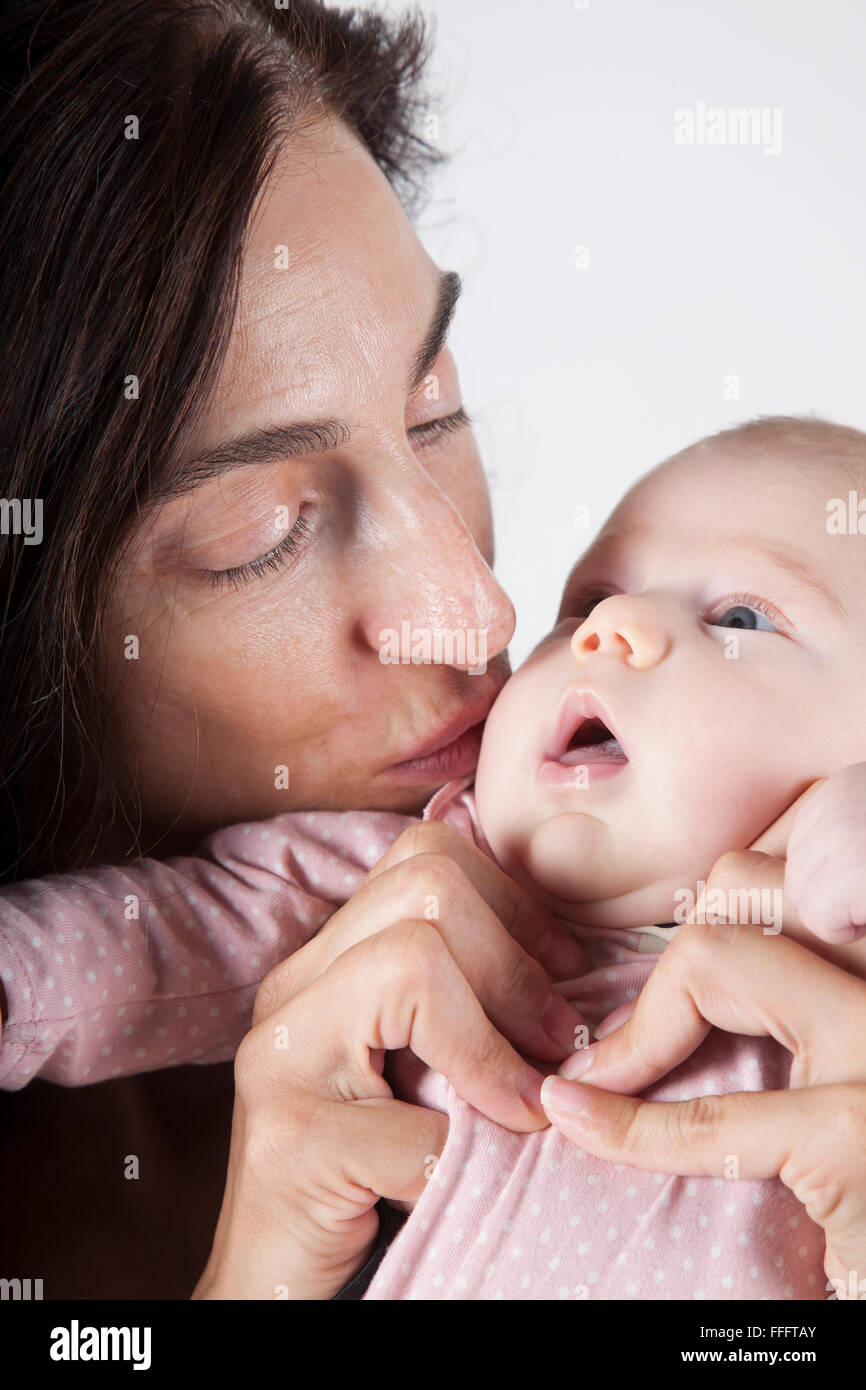 Porträt Brünette Frau küssen zwei Monate Baby offenem Mund mit rosa  Strampler shirt Stockfotografie - Alamy