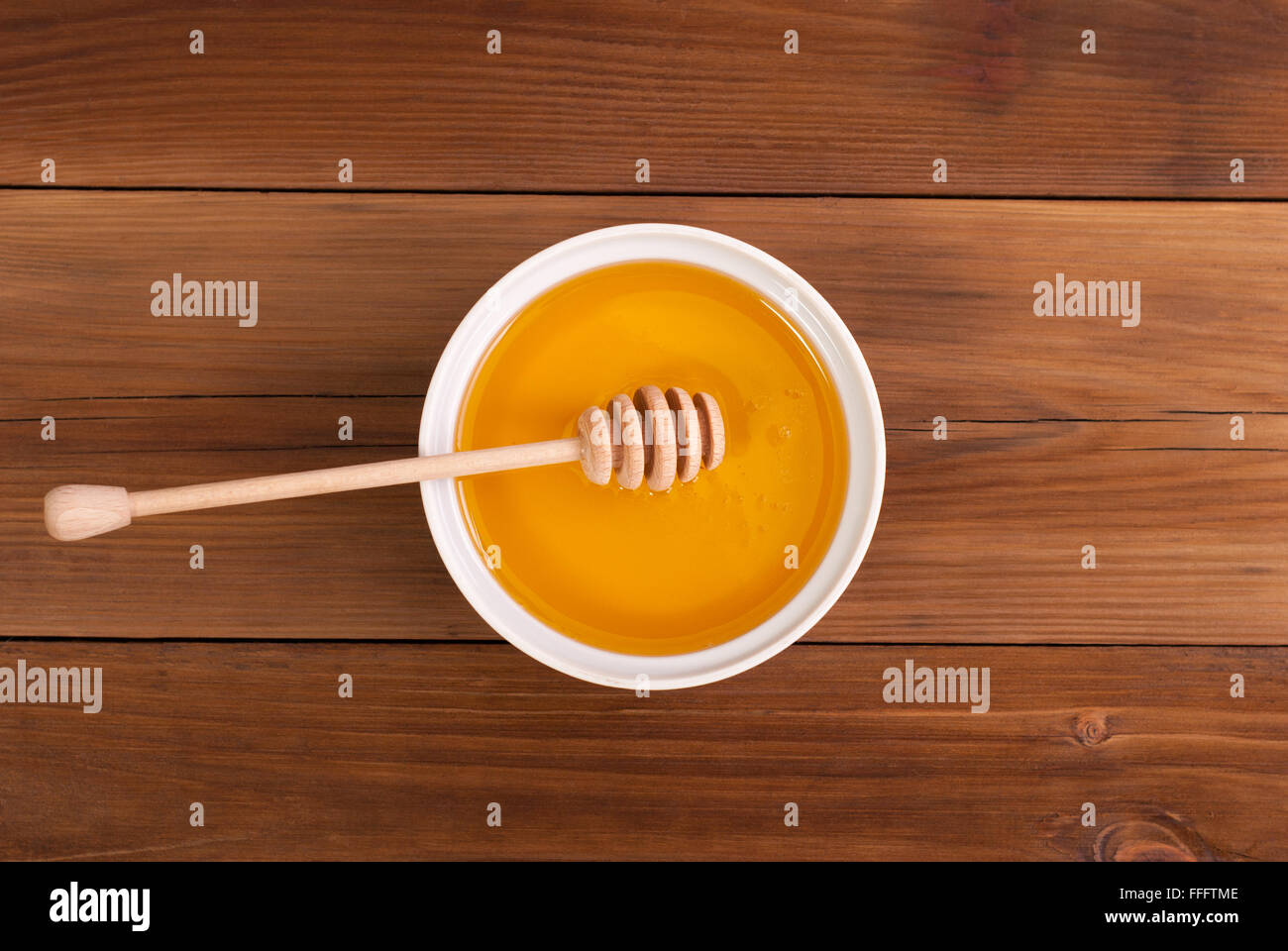 Honig in das Glas mit einem Löffel auf einem Holztisch. Ansicht von oben. Stockfoto