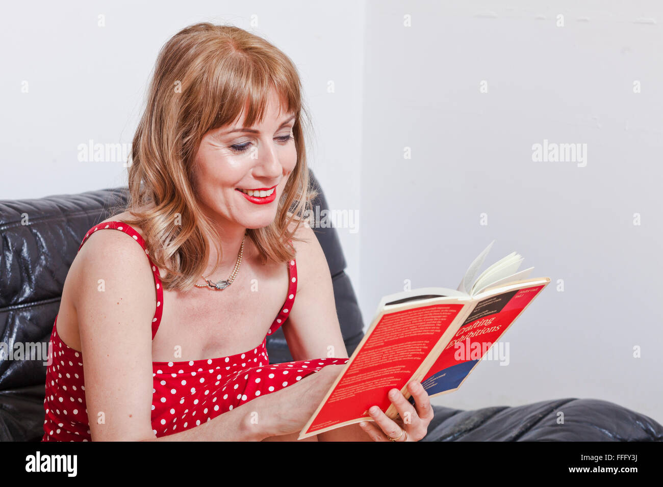 Frau liest ein Buch auf dem Sofa im Wohnzimmer. Stockfoto