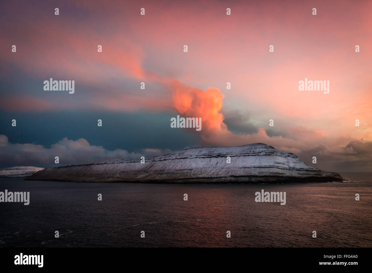 Rote Wolken auf Inseln bedeckt mit Schnee bei Sonnenuntergang: Dachreiter Island, Färöer, Dänemark, Europa Stockfoto