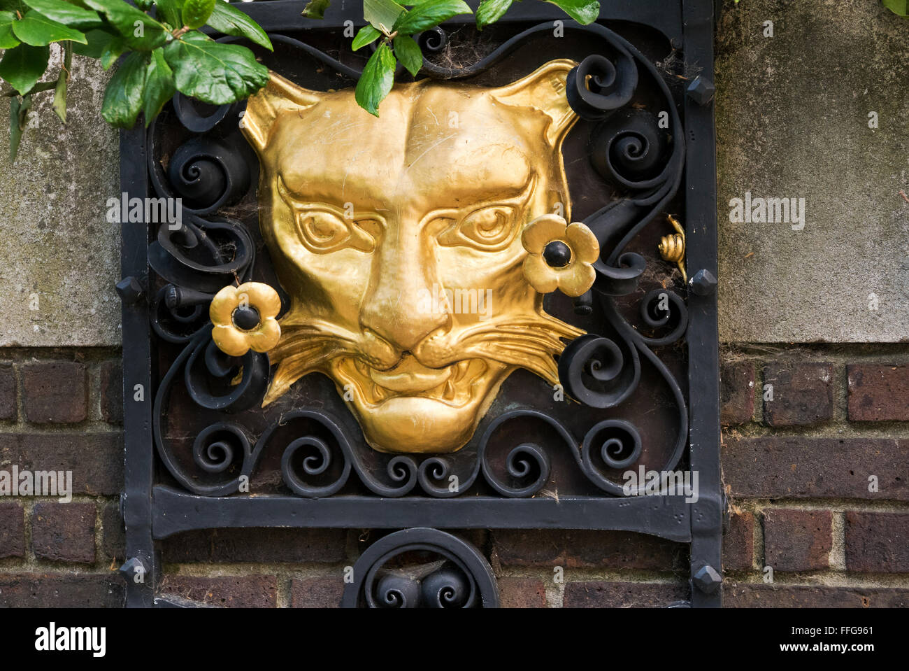 Eine Skulptur von einer Katzengesicht gemalt Gold auf einer Außenwand bei der Worshipful Company of Goldsmiths College, London. Stockfoto