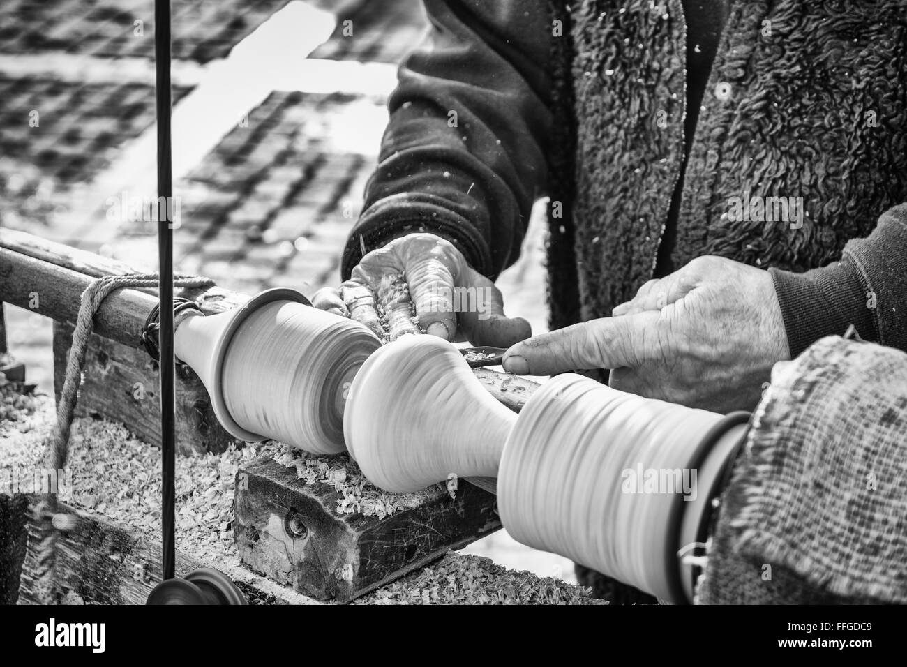 Ein Handwerker schnitzt ein Stück Holz mit eine alte manuelle Drehmaschine. Stockfoto