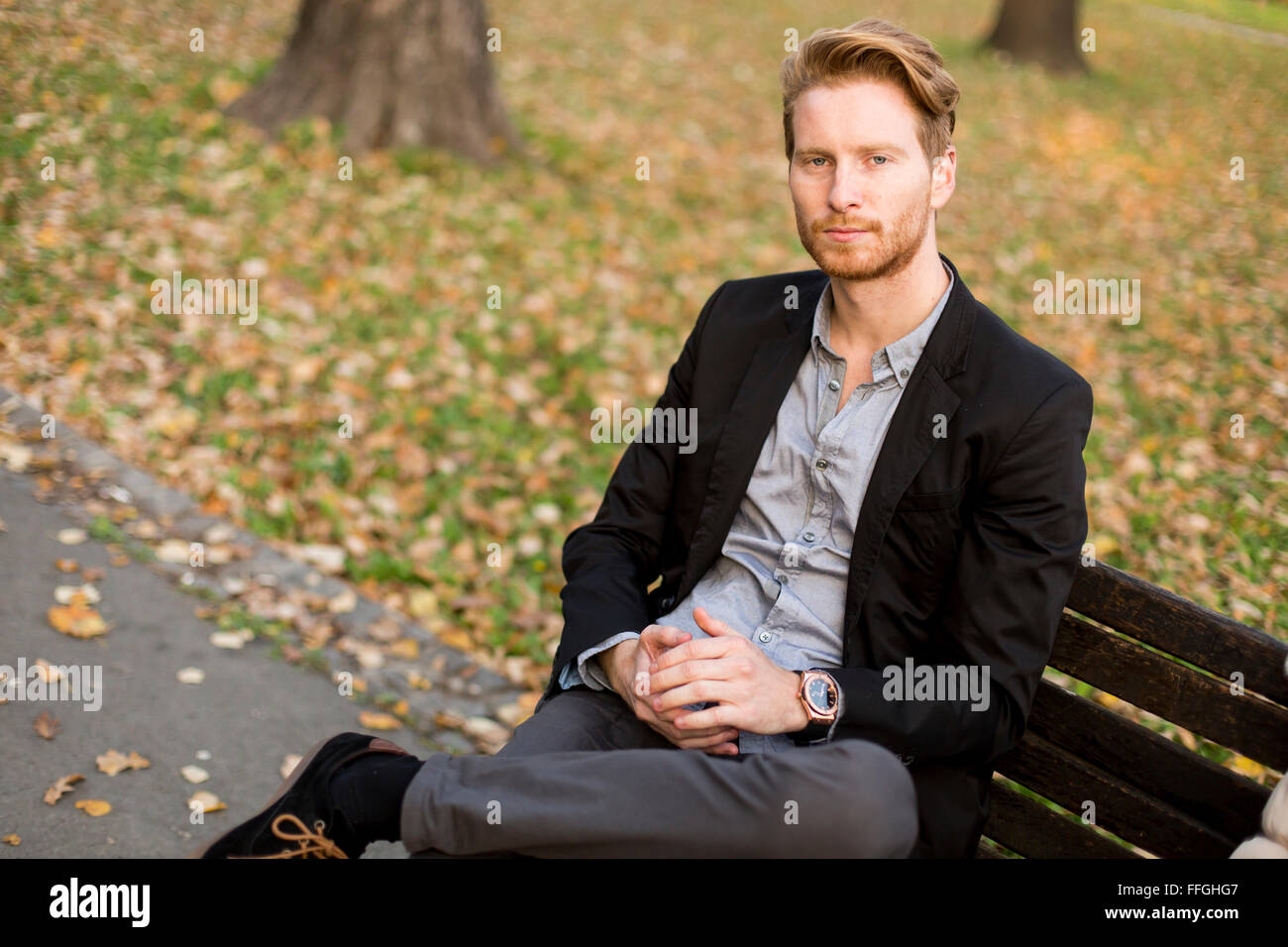 Junger Mann auf Bank im Herbst park Stockfoto