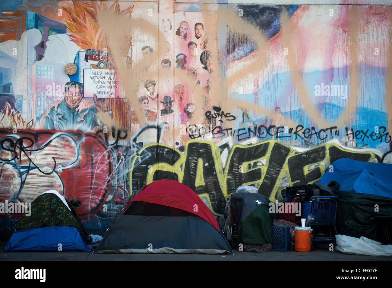 Hinter einer Reihe von Wohnbereichen von Obdachlosen Personen ein Wandbild eines Gebäudes auf Skid Row zeigt die Kultur der Stadt und umfasst das Vorhandensein der fortwährenden Problems der Obdachlosigkeit und Arbeitslosigkeit. Stockfoto