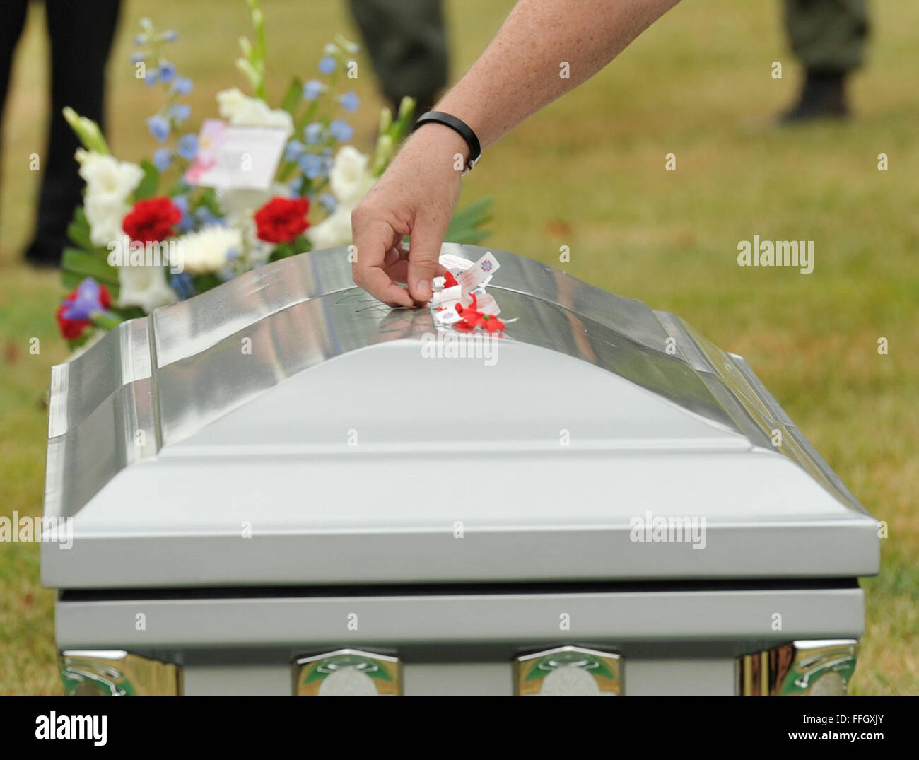 Ein Familienmitglied legt eine Blume auf den Sarg mit Überresten von sechs Flieger getötet bei einem Flugzeugabsturz in Laos am 24. Dezember 1965. Ihre Überreste wurden vor kurzem geborgen und identifiziert. Eine Trauerfeier fand 9. Juli 2012, am Nationalfriedhof Arlington, VA. Stockfoto