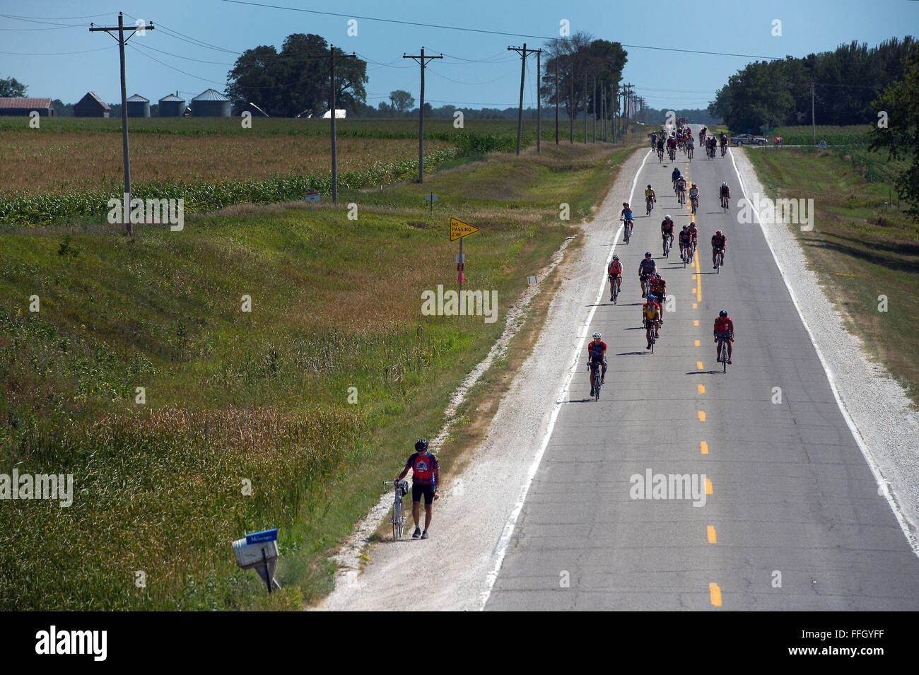 RAGBRAI Teilnehmer mitfahren Maisfelder und Bauernhäuser in der Route nach Webster City, Iowa. Einige Fahrer nicht machen es den ganzen Weg auf ihr Fahrrad und zu Fuß oder fahren mit einem Bergefahrzeug. Stockfoto