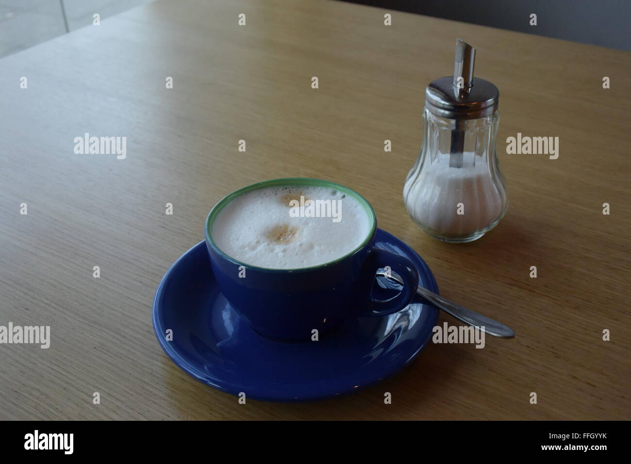 eine blaue Tasse Cappuccino mit Zucker Stockfoto