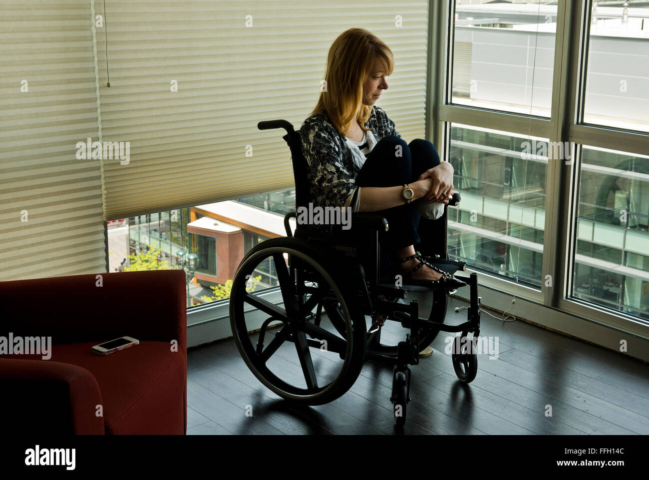 Adrianne Haslet-Davis Uhren der Hektik der Innenstadt von Boston aus einem Fenster in ihrem Apartment-Komplex. Seit der Bombardierung, Adrianne ungern ihre Heimat zu verlassen und lieber bleibt im Inneren, wo sie sich sicher fühlt. Stockfoto