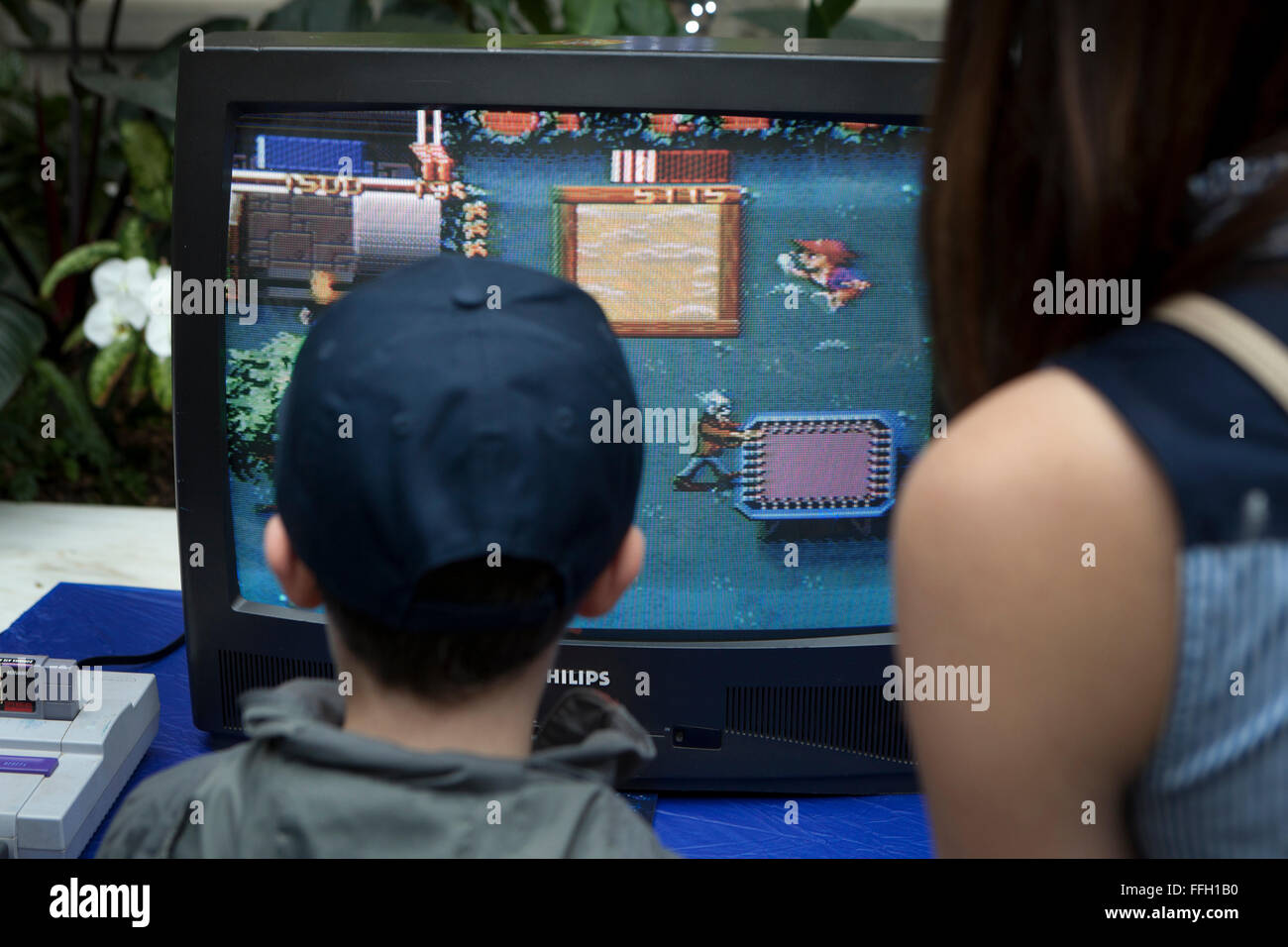Kleiner Junge und Mutter spielen Super Nintendo Videospiel - USA Stockfoto