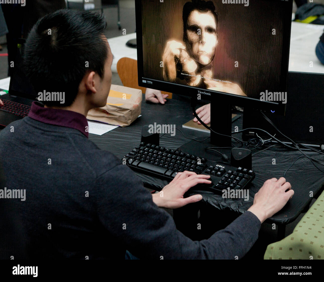 Asiatischer Mann sitzt vor dem Computer-Monitor - USA Stockfoto