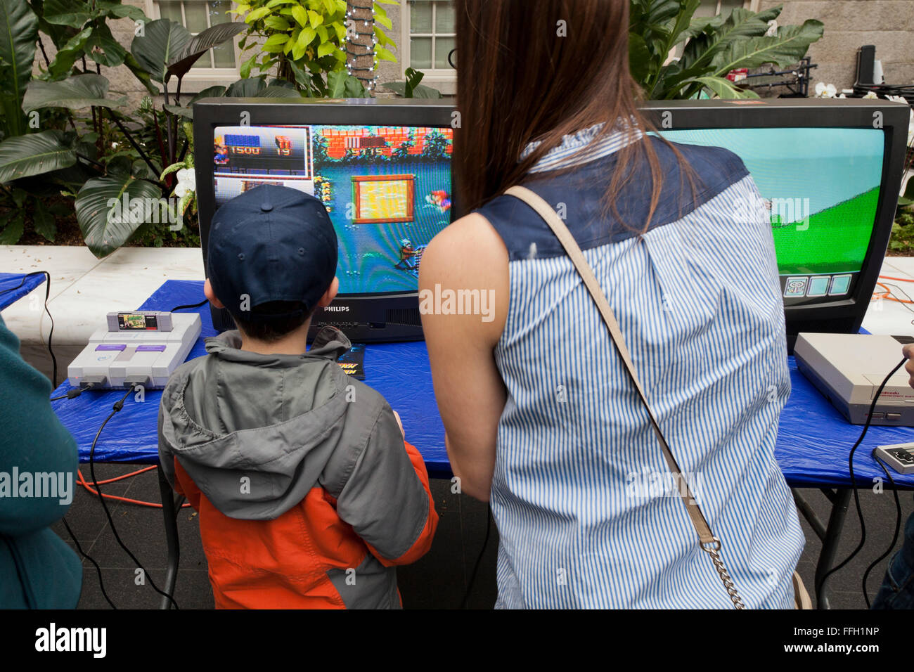 Kleiner Junge und Mutter spielen Super Nintendo Videospiel - USA Stockfoto