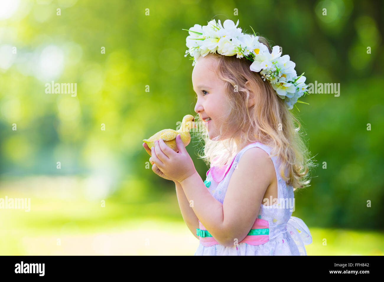 Kleines Mädchen Spaß auf Ostereiersuche. Kid im Blume Krone spielen mit Spielzeug Ente oder Huhn. Kinder, die auf der Suche nach Eiern Stockfoto