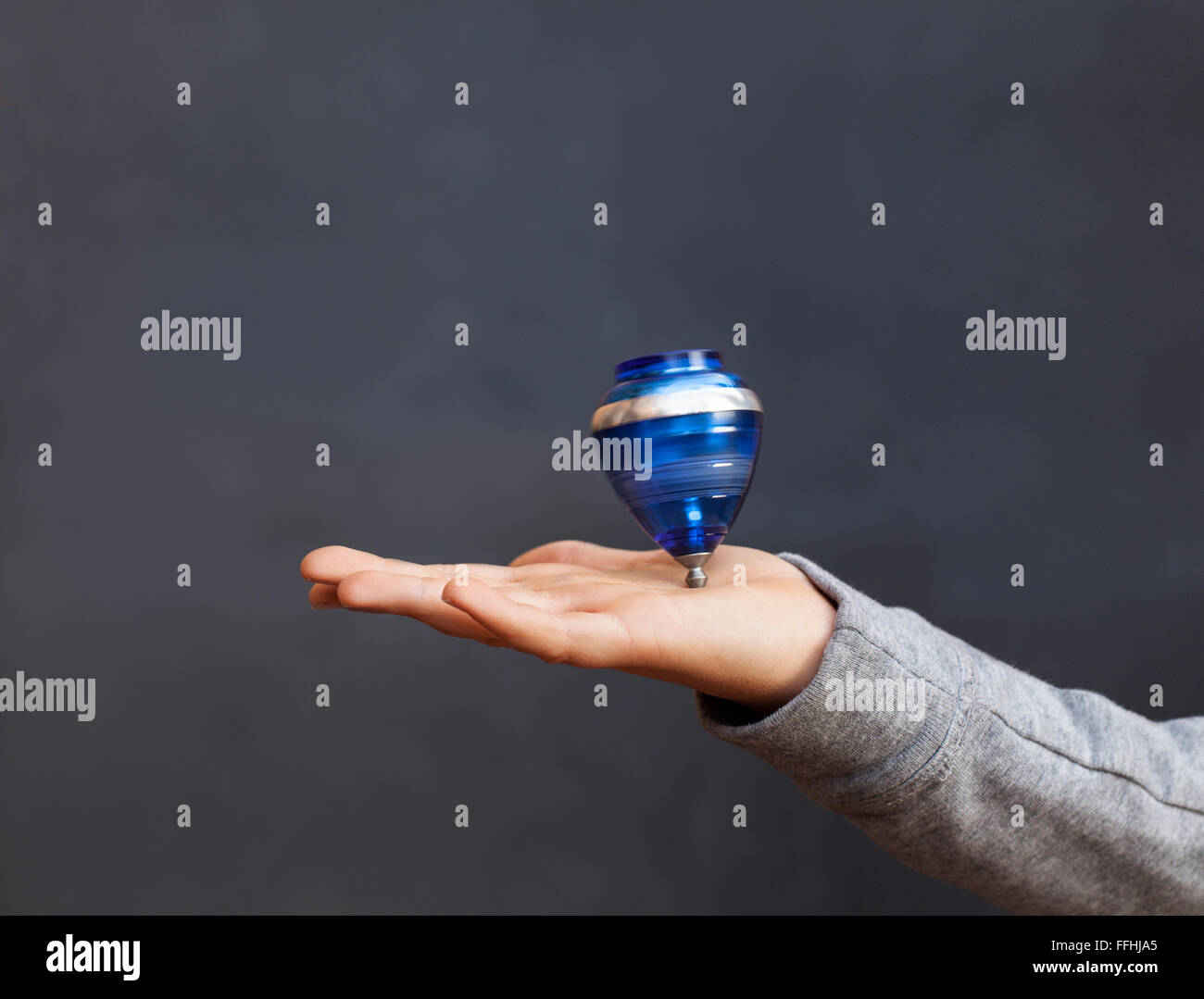Eine junge Spinining eine Spitze auf der Hand. Dunklen Hintergrund und Kopie Platz für Ihren Text. Stockfoto