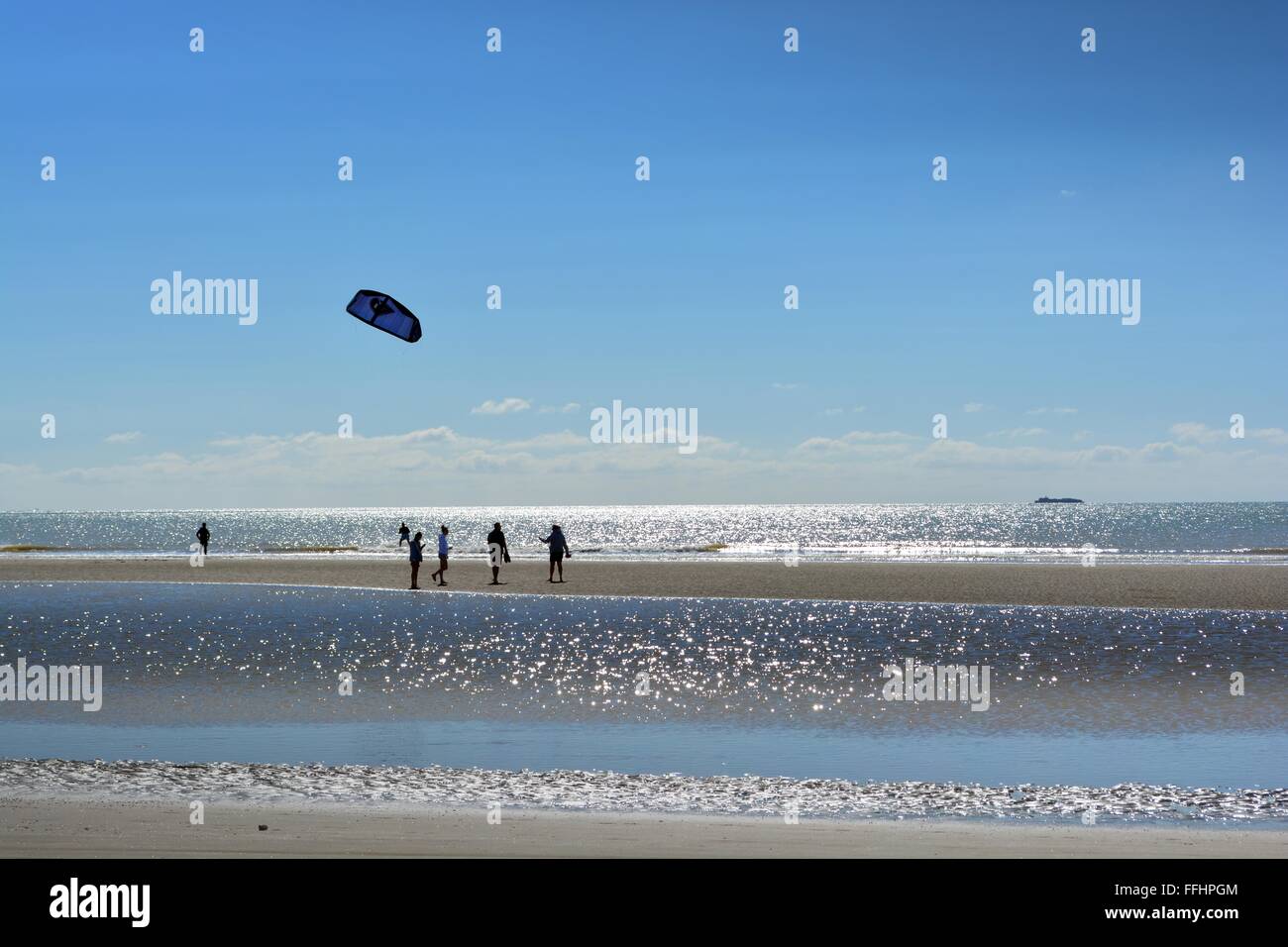 Kitesurfer bei Ebbe über eine glitzernde Meer in Camber Sands an der Südküste, Sussex, UK zu beobachten Stockfoto