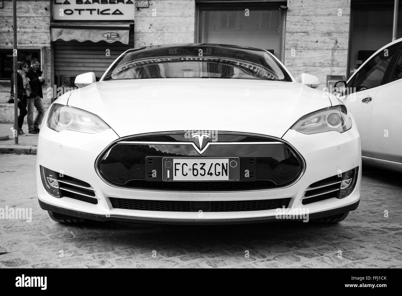 Rom, Italien - 13. Februar 2016: White Tesla Model S Auto auf städtischen Straße in Rom, Vorderansicht, Closeup, schwarz / weiß Stockfoto