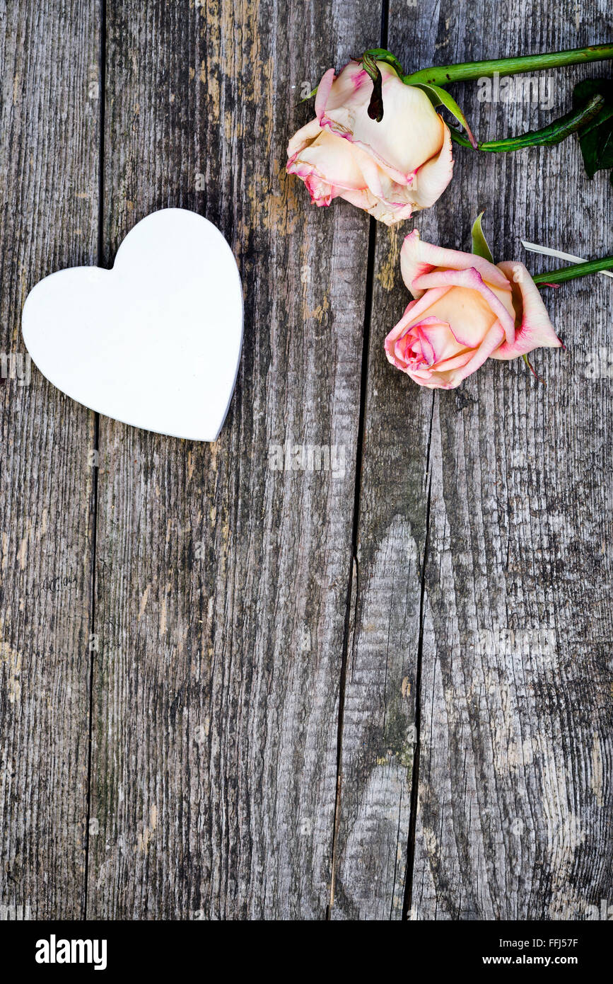 Schöne Rosen und weißen Herz aus Holz auf alten Holzbrett. Liebe-Konzept. Stockfoto