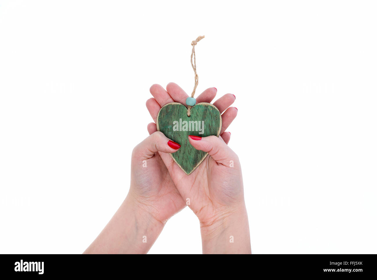 Weibliche Hände Gebens grünes Herz aus Holz. Weißen Hintergrund. Stockfoto