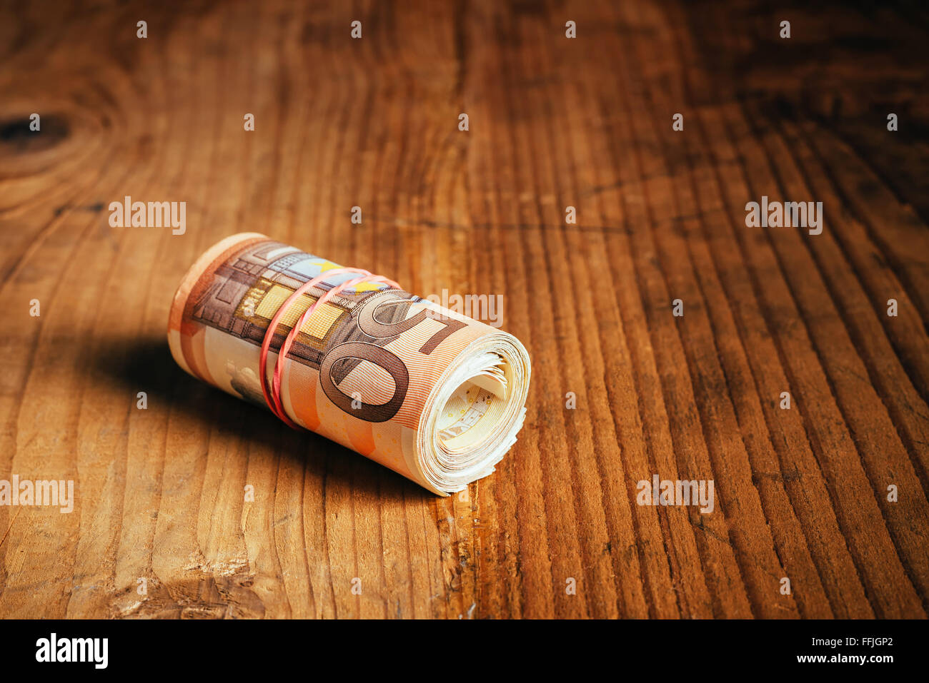 Konzept Geld sparen bares Geld mit Gummiband auf hölzernen Schreibtisch, fünfzig Euro Banknoten persönliche Haushaltsbudget Stack aufgerollt Stockfoto