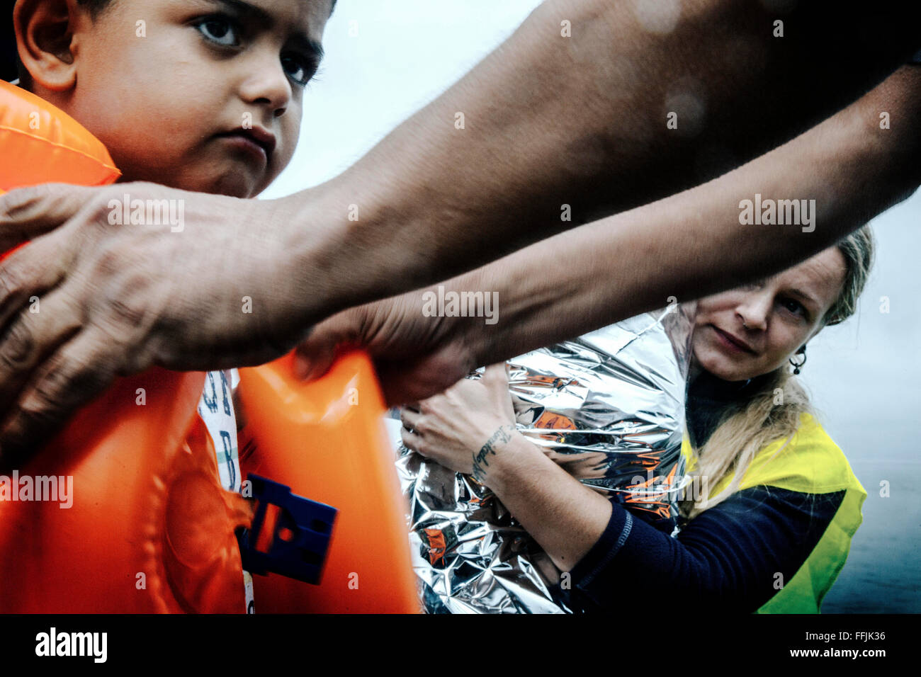 Freiwillige aus Holland hilft ein Flüchtlingskind, das gerade angekommen durch schwimmende Boot in den nördlichen Teil von Lesbos Stockfoto
