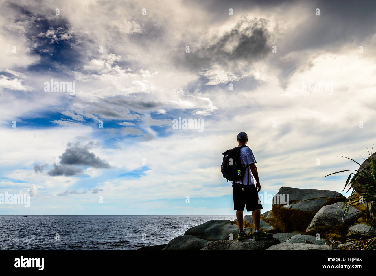 Ein Mann blickt in einen wunderschönen Abendhimmel vor der Küste von Pulau Manukan Island in Malaysia. Stockfoto