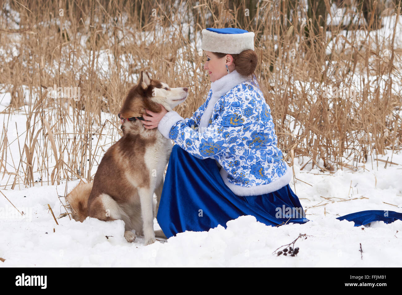 Junge Russin in traditionellen Winterkleidung mit Siberian Husky Stockfoto