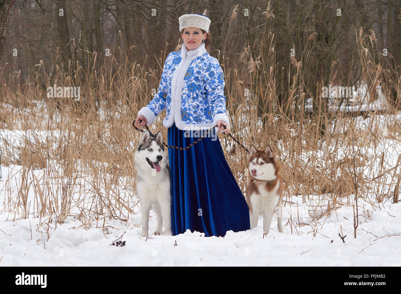 Junge Russin in traditionellen Winterkleidung mit zwei Siberian Huskies Stockfoto