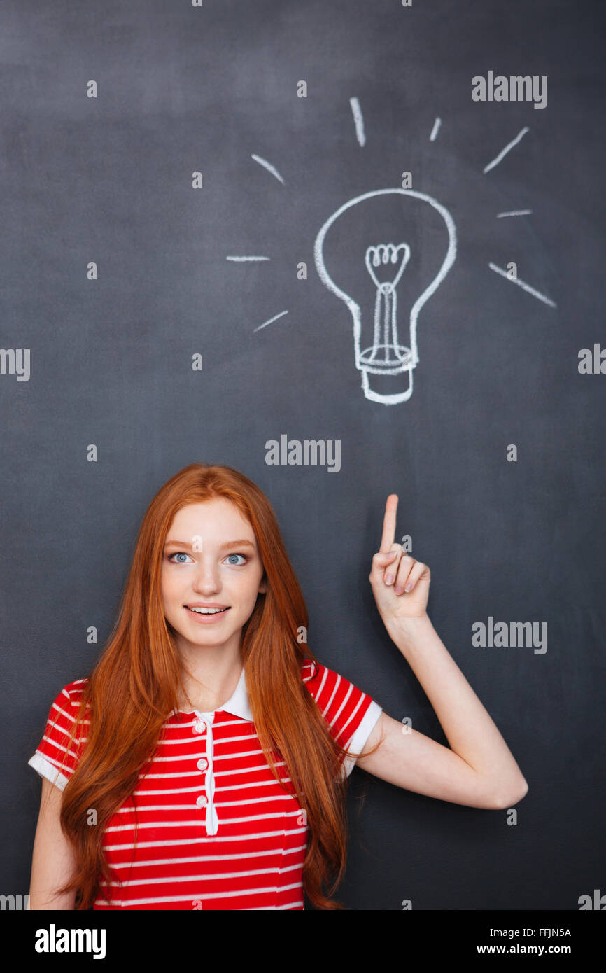 Attraktive inspiriert junge Frau mit roten Haaren nach oben und haben eine Idee über Blackboard Hintergrund Stockfoto