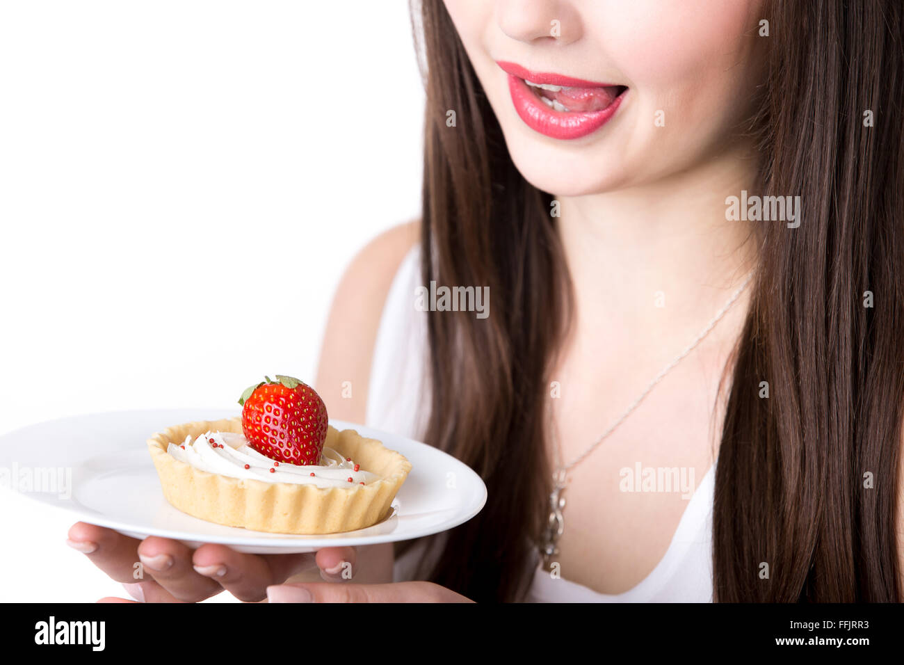 Junge Frau hält in ihrem Hand-Teller mit leckeren Erdbeer Sahne Torte Kuchen, leckte die Lippen versucht, süßes Dessert Essen Stockfoto