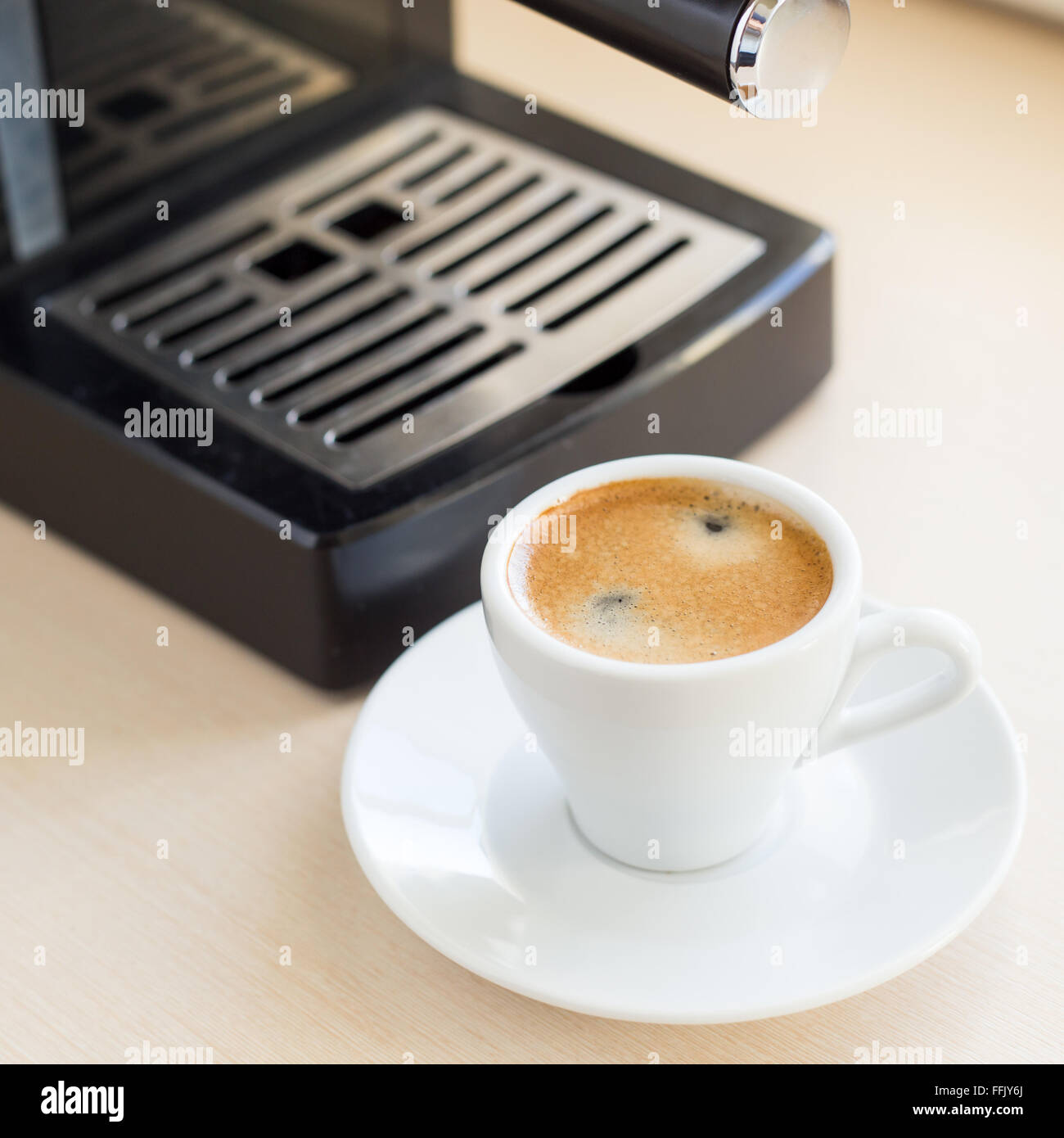 Brauen klassischen Espresso mit Kaffee aus dem Automaten. Kaffee mit braunen Schaum in kleinen weißen Tasse auf dem Küchentisch, in der Nähe von Fenster Stockfoto